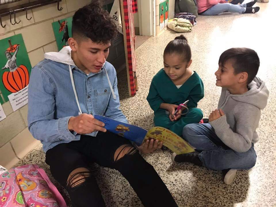 studeent reading to a younger student